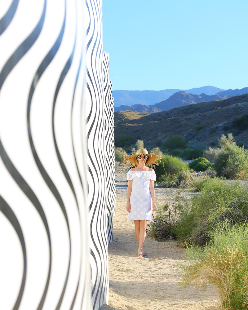 Cute Little White Dresses: Fashion blogger Kelly Golightly visits Desert X in Palm Springs wearing a Sail to Sable LWD + Lack of Color straw hat. #kellygolightly #desertx #lwd #lackofcolor #murals #littlewhitedress